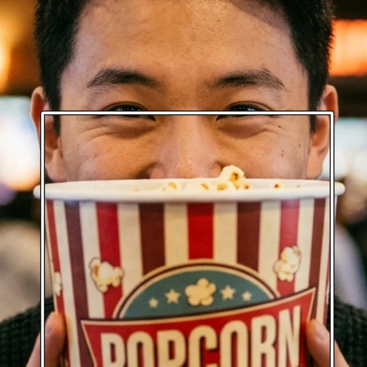 Input. The popcorn tub hides the mouth and chin; the box marks the zoomed region.